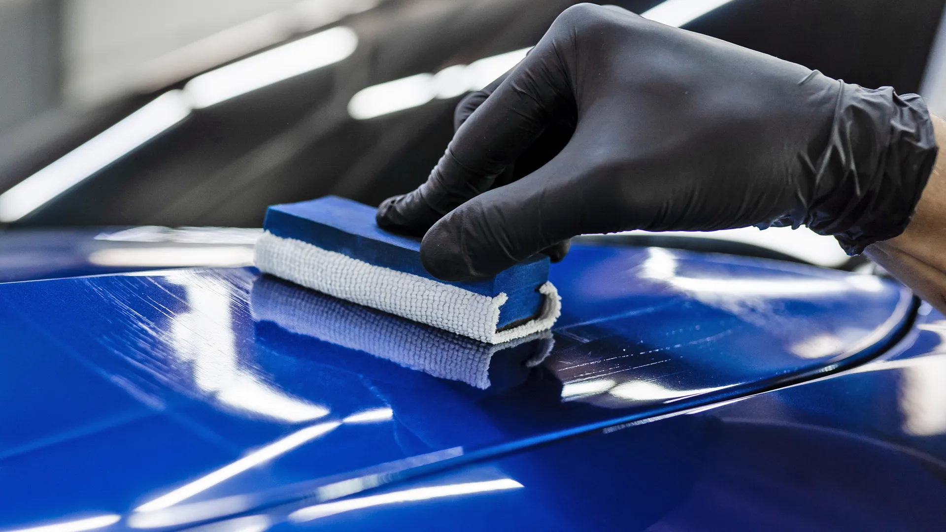 detailer applying ceramic coating to the hood of a car